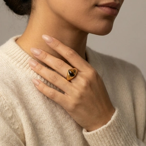 Dettaglio di un anello dorato con gemma occhio di tigre marrone sulla mano di una modella