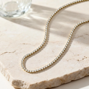 Detail einer 18k vergoldeten Tennis-Halskette mit Zirkonia auf Stein-Hintergrund