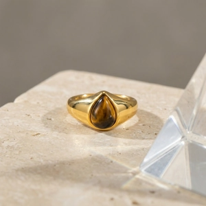 Anello dorato minimalista con occhio di tigre a goccia su una base in pietra naturale