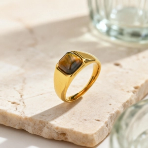 Dettaglio di pietra occhio di tigre su anello vintage dorato posizionato su vassoio di pietra