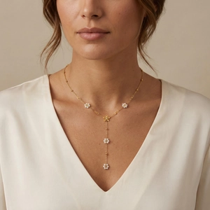 Elegante collana a Y dorata con fiori di perle indossata su una camicetta di seta a V