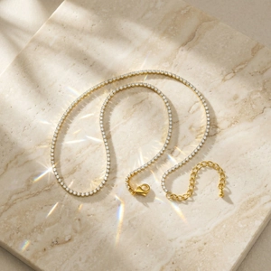 Detail einer goldenen Tennis-Halskette mit Zirkonia und Karabinerverschluss auf Marmor