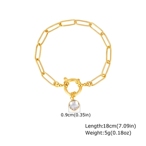 Detail of a gold paperclip chain bracelet with a heart toggle and crystal pendant