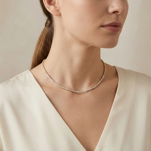 Nahaufnahme der goldenen Tenniskette mit funkelnden Zirkoniasteinen am Ausschnitt des Models