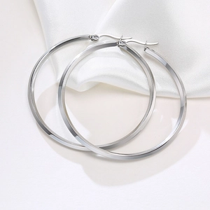 Detailed view of polished silver hoop earrings on white silk background with hinge clasp