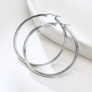 Macro shot of large polished silver hoop earrings with a flat square-edge design on white ceramic