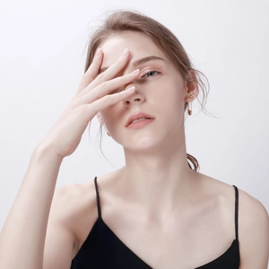 Close-up of golden safety pin earrings on a model showing industrial style detail