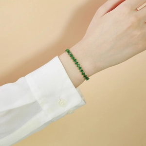 Elegantes Gold-Titanstahl-Armband mit ovalen grünen Zirkonia an einem Handgelenk