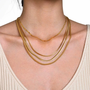 Detalle de collares dorados en capas con texturas de cadena de serpiente, caja y trigo en modelo