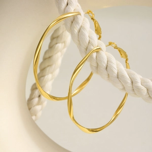 Golden Mobius twist hoop earrings in stainless steel hanging on a white cotton rope