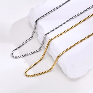 Detalle de cadenas de caja de 2mm en acero inoxidable oro y plata sobre piedra