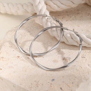 Macro view of silver mobius twisted hoop earrings on textured stone background