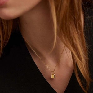 Minimalist gold titanium steel necklace with small padlock pendant shown on neck