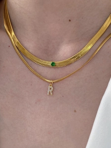 Dettaglio della collana a catena serpente dorata con pietra verde e ciondolo lettera R