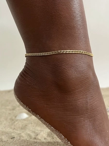 Flat gold snake chain anklet on ankle with high-gloss finish for beach vacation style