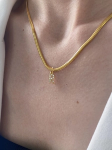 Dettaglio della collana a serpente dorata con pendente a lettera R di cristalli sul collo