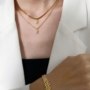 Layered gold necklaces with letter R pendant and chunky chain bracelet on model
