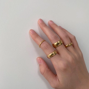 Close-up of minimalist 18K gold plated tungsten rings in various widths on female model