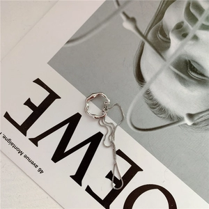 Unregelmäßiger silberner Metallring mit Kette auf einem minimalistischen Modemagazin