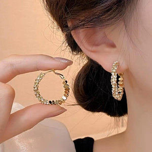 Geometrische goldene Creolen mit Zirkonia-Besatz und Pailletten, getragen am Ohr