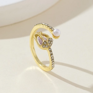 Close-up of golden tulip ring with purple heart stone, white pearl and crystal accents