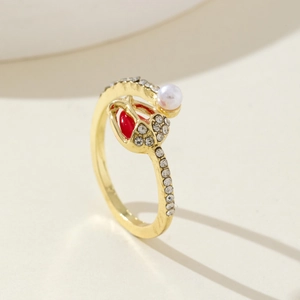 Detail of gold tulip ring featuring a red heart bud, white pearl, and pavé zircon stones