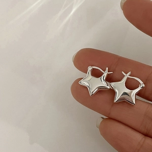 Pendientes de aro con estrella en plata de ley S925 pulida mostrados en el dedo
