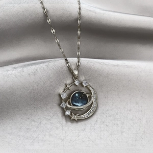 Macro detail of planet pendant with blue marble texture on silver satin background
