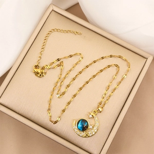 Elegante gouden maan en ster ketting met sprankelende diamanten en blauwe hanger