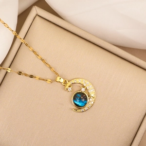 Ketting met maan, ster, blauwe steen en kristallen op een gouden sieradendoosje