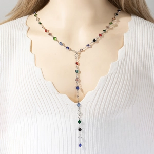Long Y-shaped necklace with colorful crystals on a silver chain worn over a white knit top