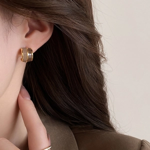 Close-up of vintage brown resin hoop earrings with gold trim worn by a model in a suit