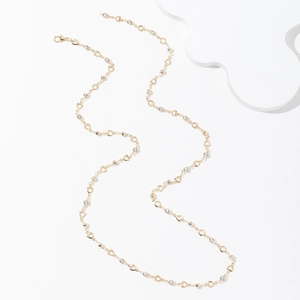 Elegante collana lunga con nappe dorate, maglie a cuore traforate e zirconi scintillanti