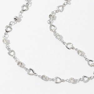 Dettaglio delle maglie a cuore e zirconi scintillanti su una collana in argento