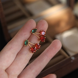 Elegante Kirschohrstecker mit rotem Zirkonia und grünem Blatt in der Hand