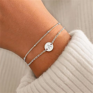 Double-layered stainless steel bracelet with letter A pendant on a white knit background