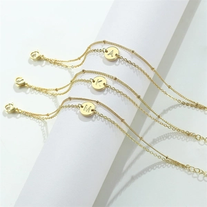 Double-layered gold stainless steel bracelet featuring round initial letter pendants