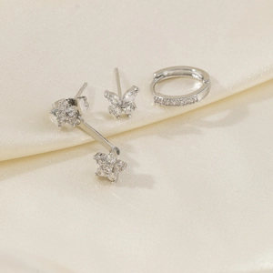Close-up of asymmetric star and moon earrings set with zircons on silk fabric
