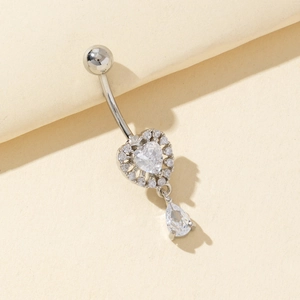 Polished silver heart belly ring with teardrop zircon pendant shown on beige paper