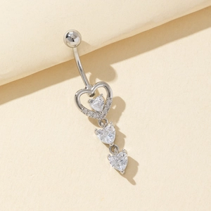 Piercing de ombligo de corazón plateado con circonitas blancas sobre fondo beige suave