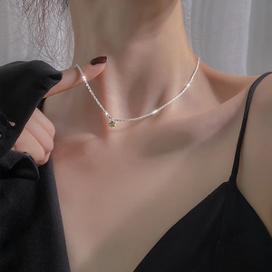 Sparkling silver necklace with round green gemstone pendant worn on neck