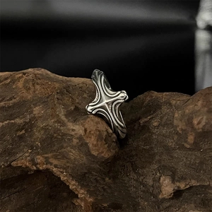 Bague croix gothique en argent vieilli posée sur un bloc de bois naturel