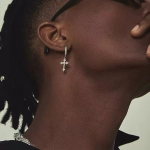 Close-up of a silver cross earring with pave-set zircons worn by a model in hip-hop style