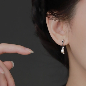 Orecchini pendenti con perle a goccia d'argento indossati con stile elegante
