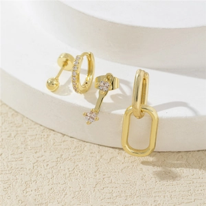Lot de quatre boucles d'oreilles géométriques dorées avec zircons étincelants sur socle blanc