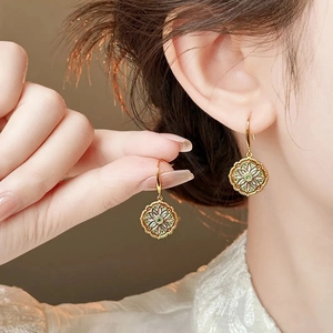 Detailed macro shot of vintage gold flower earrings with green enamel floral center