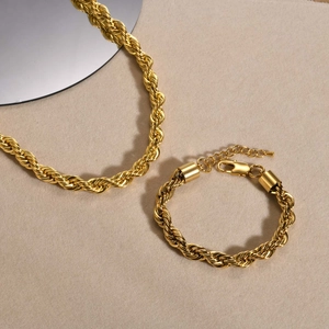 Detailed view of 8mm golden rope chain necklace and bracelet set on a textured background