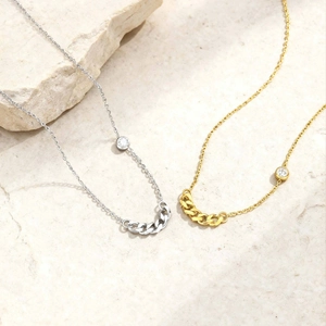 Detail of gold and silver cross necklaces with curb chain links and single zircon accent