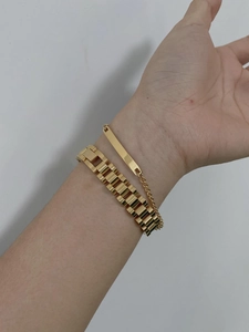 Close-up of gold chain bracelet set featuring thick watch band style and minimal bar plate