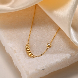 Detail of 18K gold chain link and sparkling zircon stone on a luxury stone surface